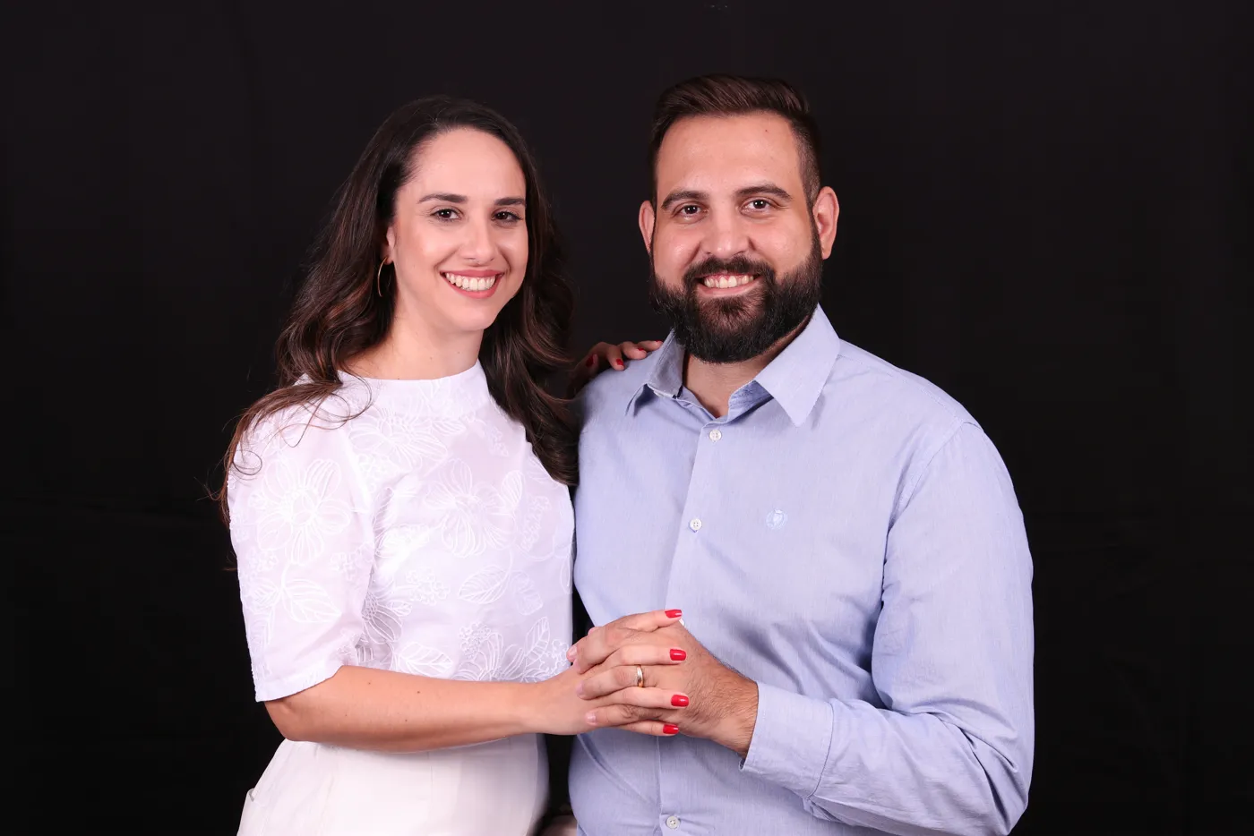 Warlen Miiller e a esposa, Carol, sorrindo em um ensaio fotográfico com fundo preto